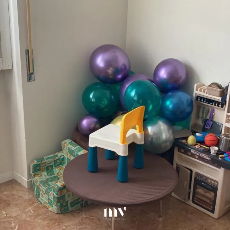 Angolo gioco di casa con palloncini colorati, un tavolino e una cucina giocattolo