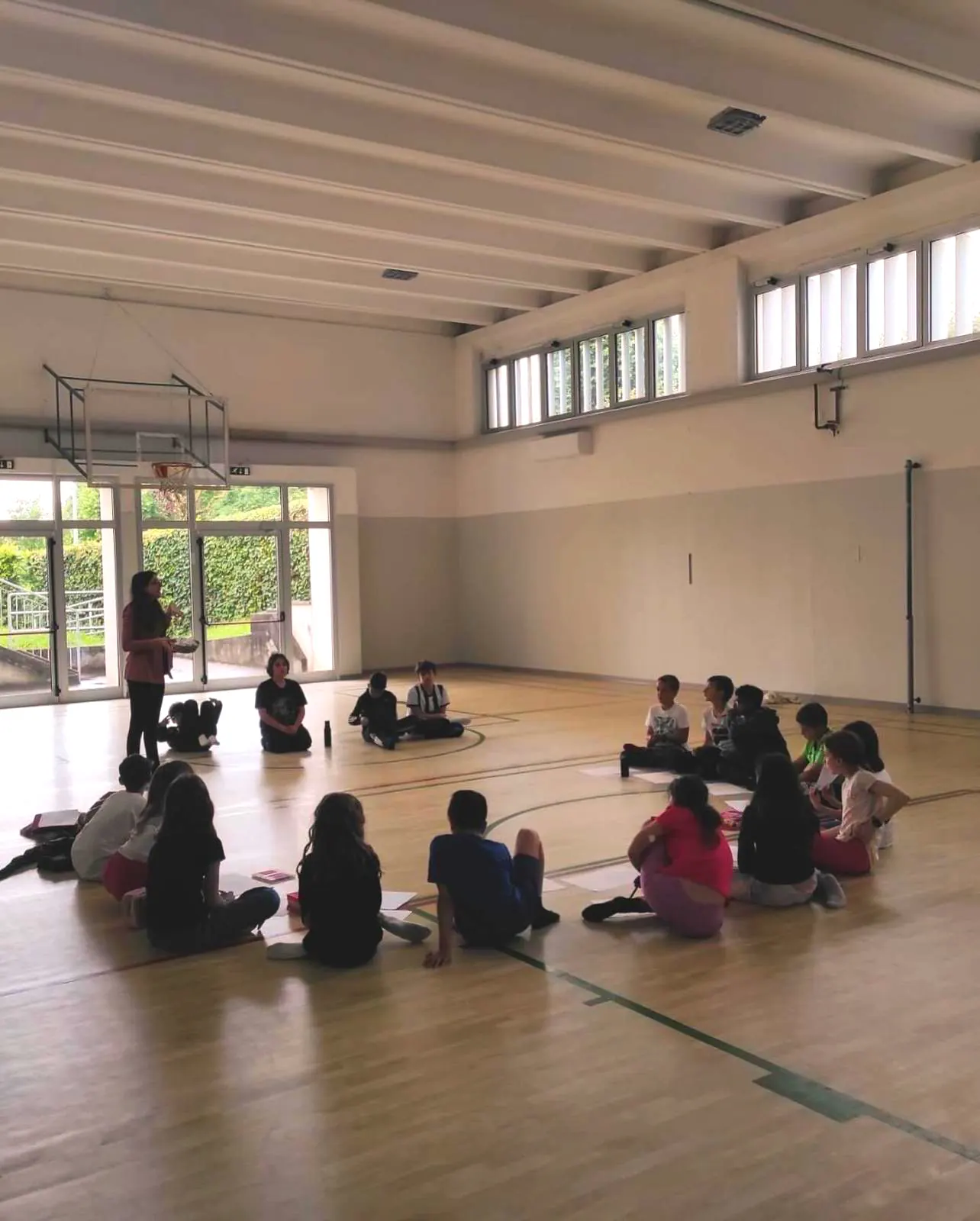 Ragazzi seduti in cerchio a terra in una palestra durante un incontro del percorso